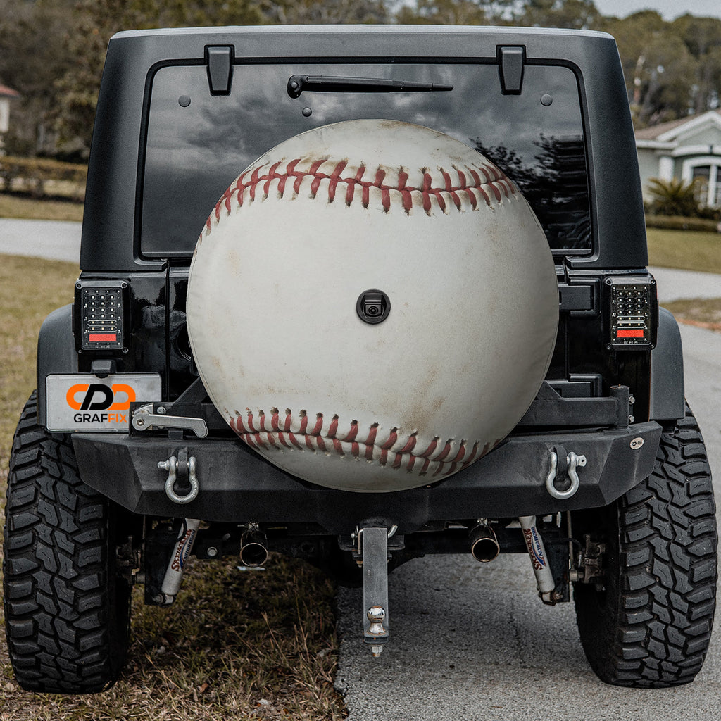 Baseball spare tire cover mounted on black Jeep Wrangler rear with backup camera cutout
