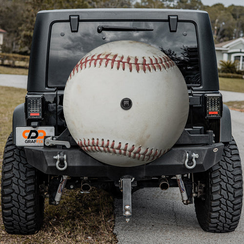 Baseball spare tire cover mounted on black Jeep Wrangler rear with backup camera cutout