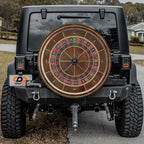 a black Jeep Wrangler with a large, round, and colorful roulette wheel attached to the rear of the vehicle.