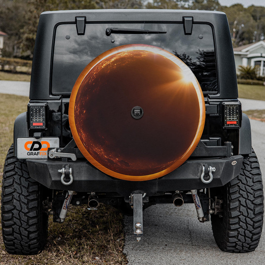 a black Jeep Wrangler with a large orange spare tire attached to the rear of the vehicle.