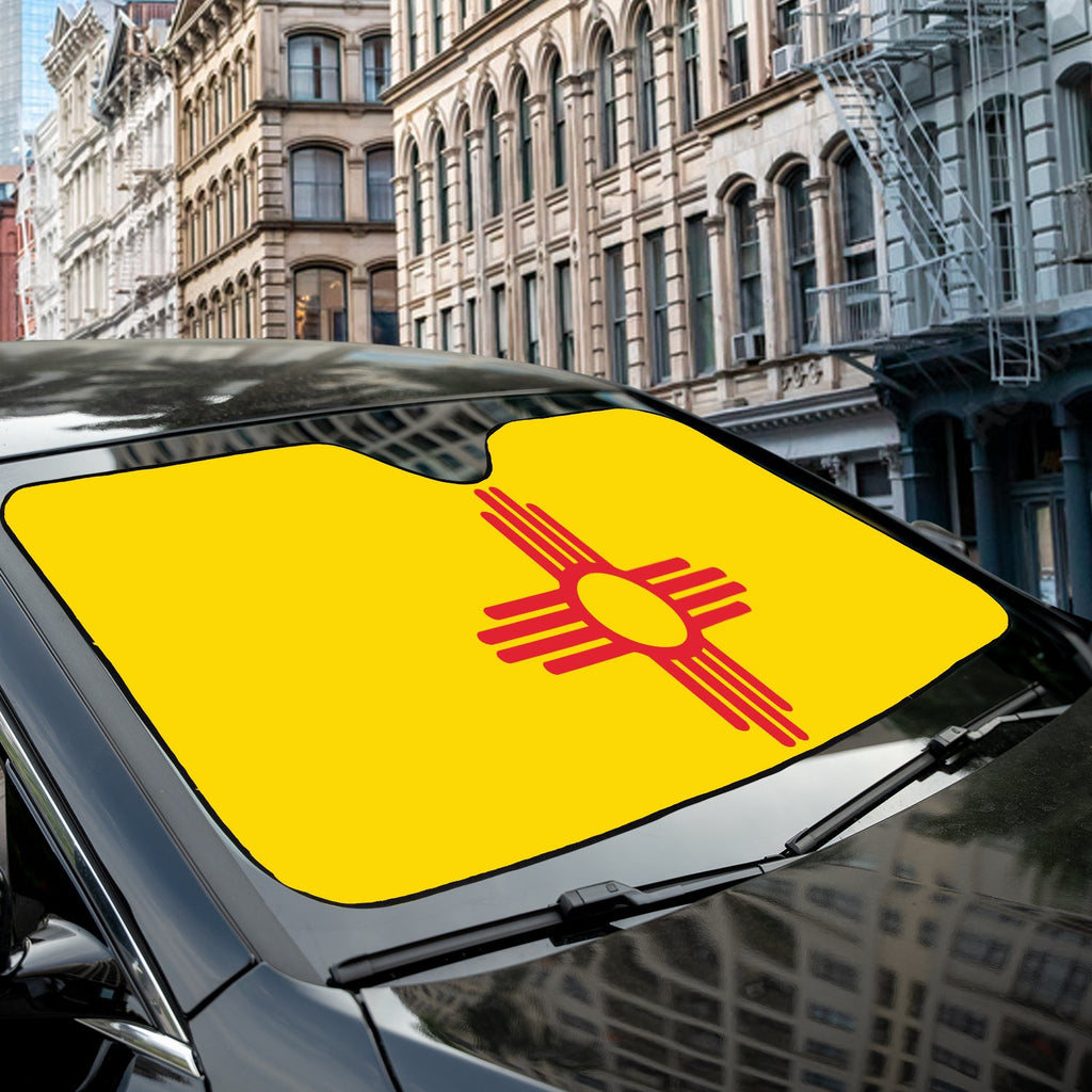 Yellow New Mexico Zia sun flag accordion windshield sunshade installed on a car in a sunny city street
