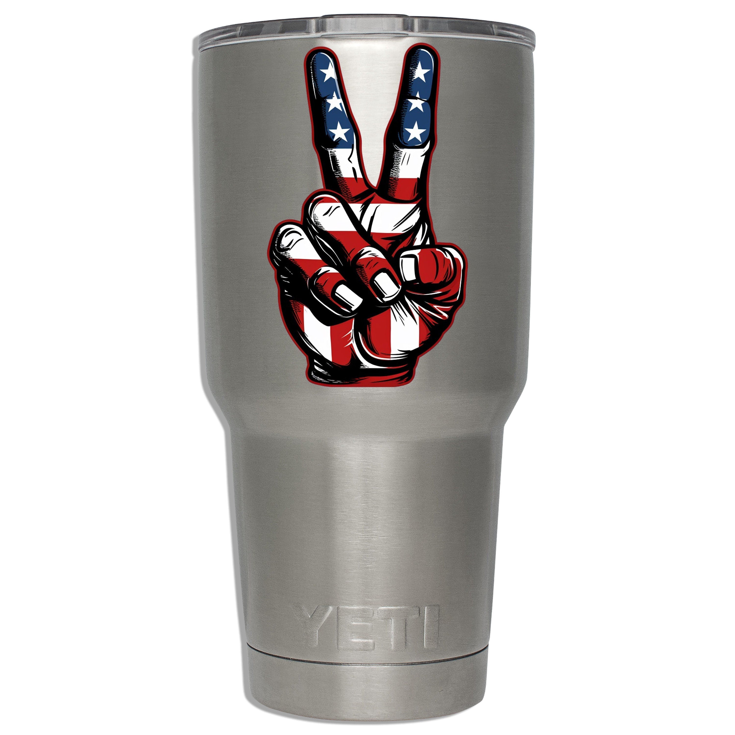 American-flag peace-sign decal mounted on a stainless YETI tumbler to show sticker size on insulated drinkware