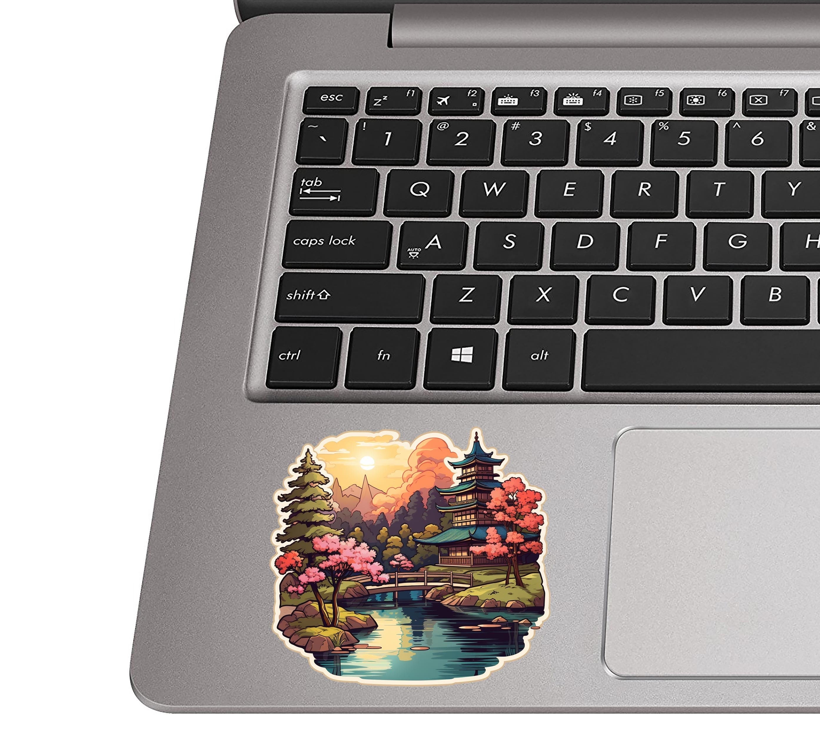 Japanese garden scene sticker placed on a silver laptop palm rest near the trackpad to show sticker scale
