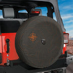 Topographic map tire cover on black Jeep Wrangler showing orange topo contour lines and compass design